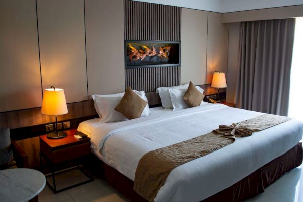 This image features a cozy hotel room with a large bed, two bedside tables with lamps, and a decorative wall display behind the bed.