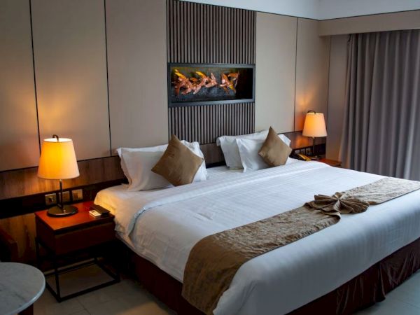 This image features a cozy hotel room with a large bed, two bedside tables with lamps, and a decorative wall display behind the bed.