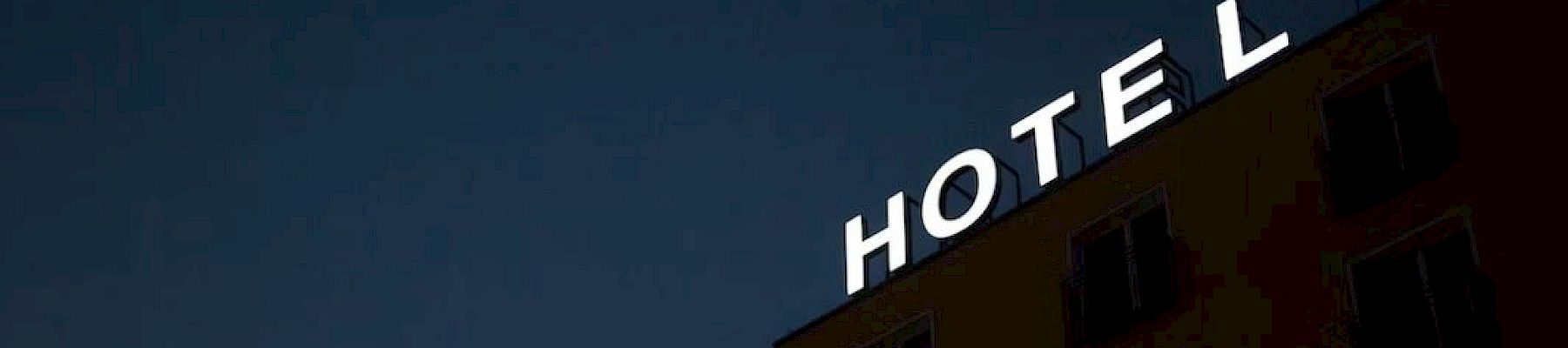 A building with an illuminated "HOTEL" sign at night, with the letter "L" unlit.