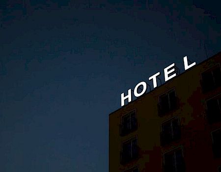 A building with an illuminated "HOTEL" sign at night, with the letter "L" unlit.