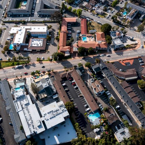 This aerial photo shows a suburban area featuring multiple buildings, roads, and parking lots, with a mix of residential and commercial structures.