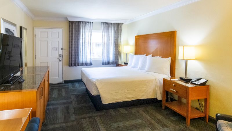A hotel room with a king-size bed, TV, and desk.
