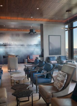 A modern lounge with comfortable seating, large windows offering scenic views of water and a Ferris wheel, and contemporary decor.